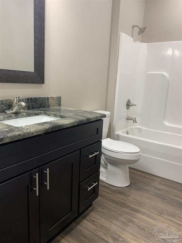 full bathroom with washtub / shower combination, vanity, toilet, and wood finished floors