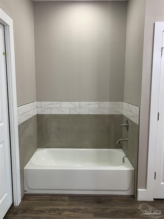 bathroom with a garden tub and wood finished floors