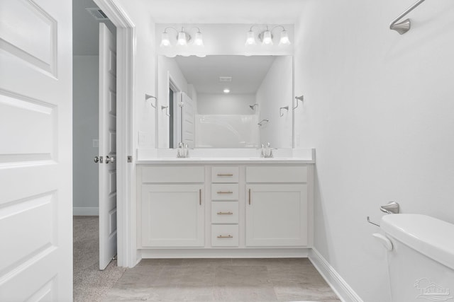 bathroom with toilet and dual bowl vanity