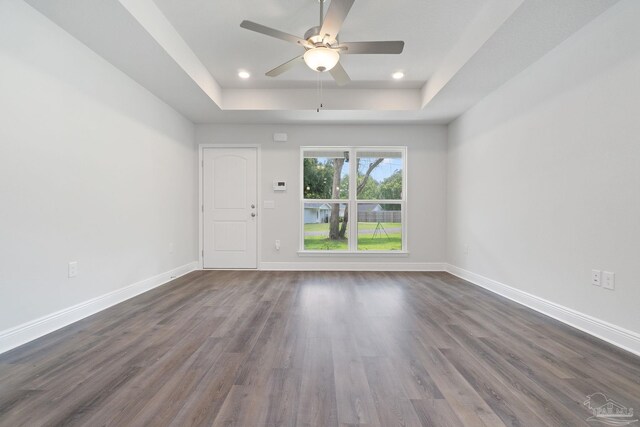 empty room featuring hardwood / wood-style floors, ceiling fan, and a raised ceiling