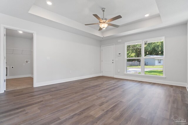 unfurnished room featuring hardwood / wood-style flooring, a healthy amount of sunlight, a raised ceiling, and ceiling fan