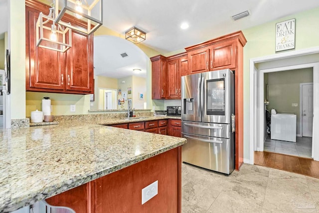 kitchen with stainless steel fridge with ice dispenser, light stone counters, kitchen peninsula, pendant lighting, and light hardwood / wood-style floors