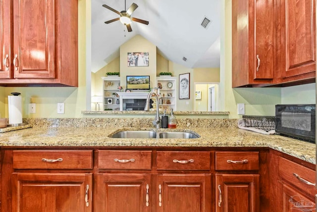 kitchen with light stone countertops, ceiling fan, lofted ceiling, and sink