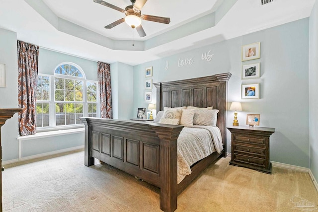 carpeted bedroom featuring a tray ceiling and ceiling fan