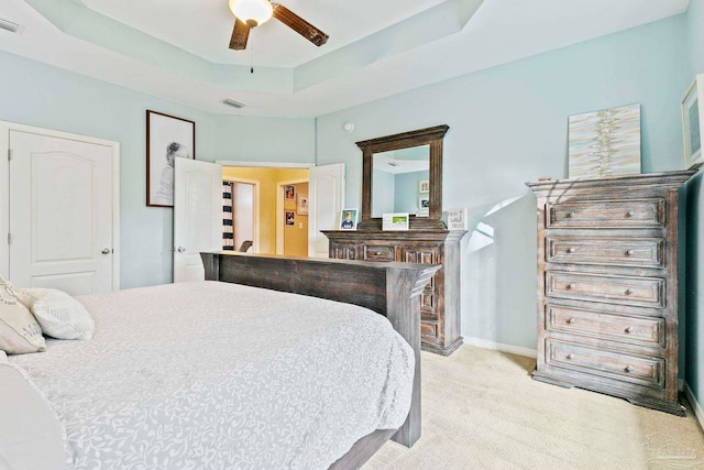 carpeted bedroom featuring a raised ceiling and ceiling fan