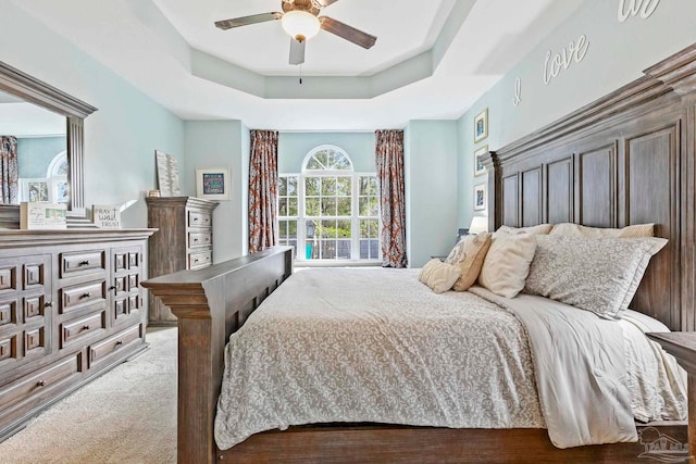 bedroom with a tray ceiling, ceiling fan, and light hardwood / wood-style flooring