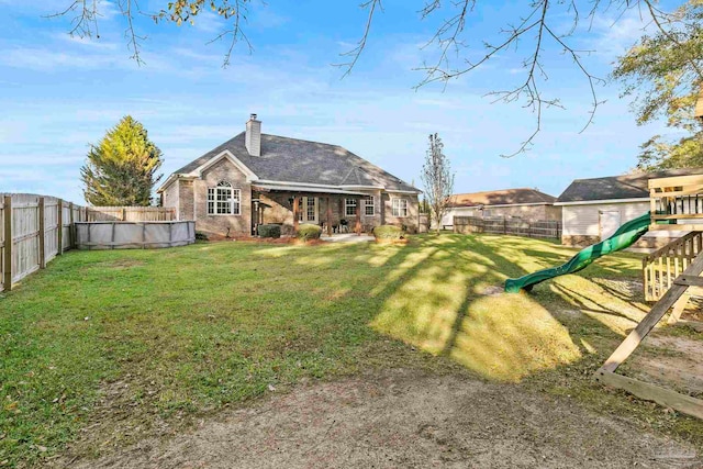 rear view of house with a fenced in pool, a playground, and a yard