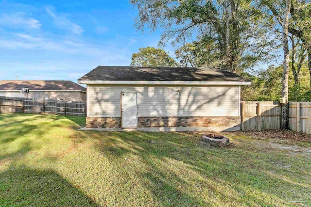 view of outdoor structure with a yard and an outdoor fire pit