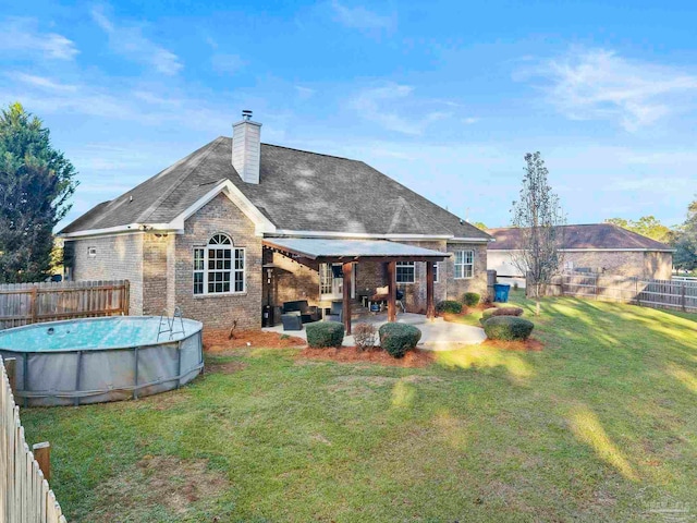 rear view of house with a fenced in pool, a patio area, outdoor lounge area, and a lawn