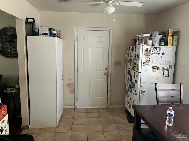 kitchen featuring light tile patterned floors, white cabinets, ceiling fan, and white fridge