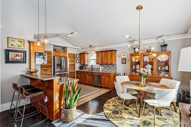 dining room with vaulted ceiling, crown molding, and dark hardwood / wood-style floors