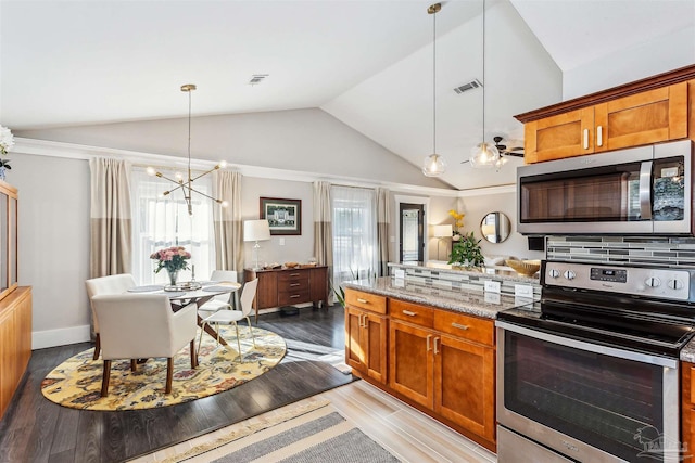 kitchen featuring tasteful backsplash, vaulted ceiling, pendant lighting, stainless steel appliances, and light stone counters