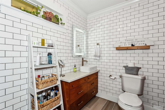 bathroom with toilet, hardwood / wood-style floors, tile walls, crown molding, and vanity