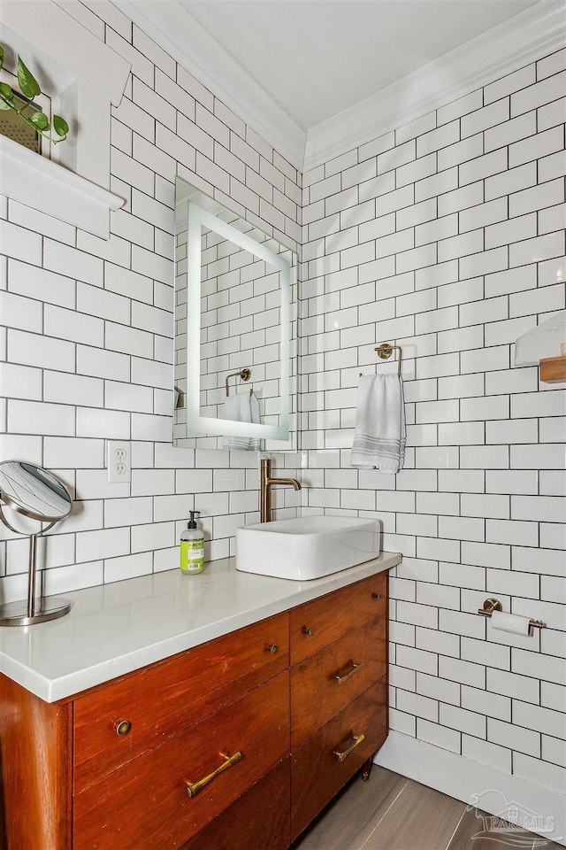 bathroom with hardwood / wood-style floors, backsplash, tile walls, crown molding, and vanity