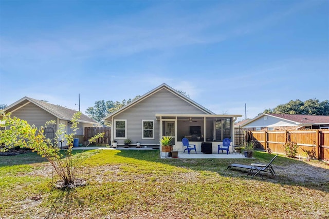 rear view of property featuring a patio area, a sunroom, and a lawn