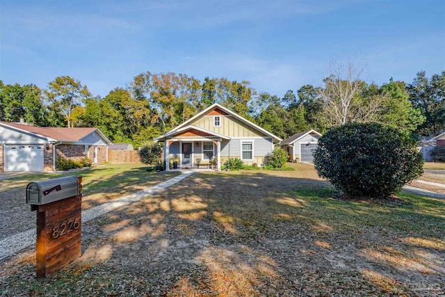 view of front of home featuring covered porch, a garage, and a front lawn