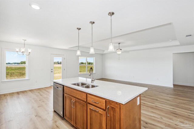 kitchen with decorative light fixtures, stainless steel dishwasher, a sink, and light wood-style floors