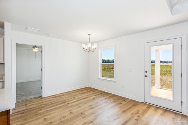unfurnished dining area with light wood finished floors, baseboards, and an inviting chandelier