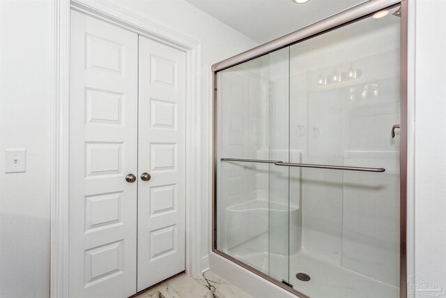 bathroom featuring marble finish floor and a stall shower
