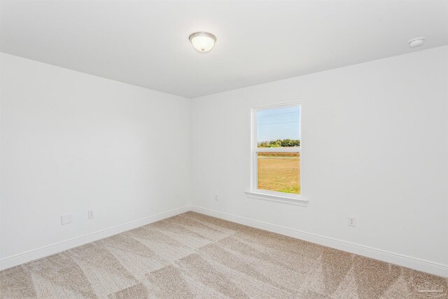 spare room with baseboards and light carpet