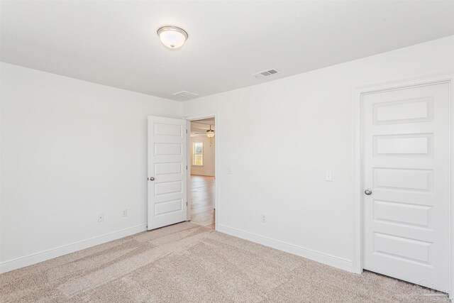 spare room featuring light carpet, visible vents, and baseboards