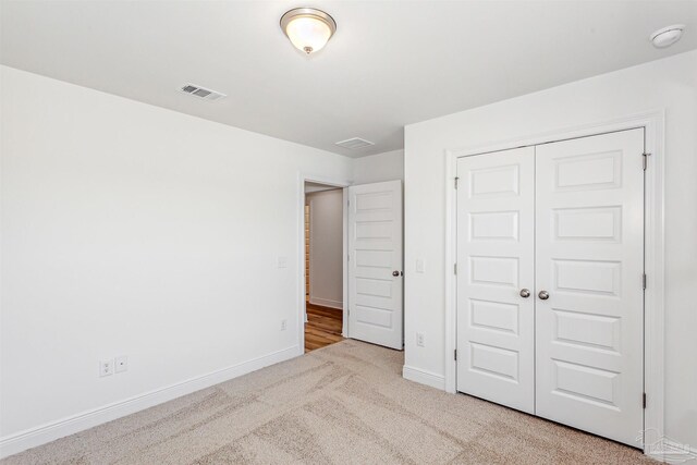 unfurnished bedroom with a closet, carpet floors, visible vents, and baseboards