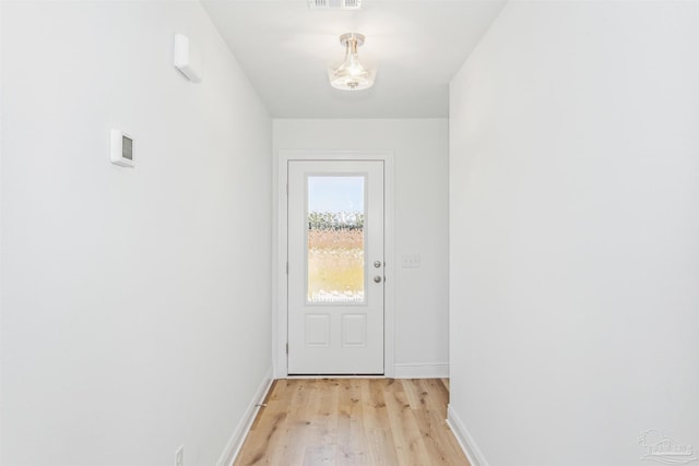 doorway with light wood-style floors, visible vents, and baseboards