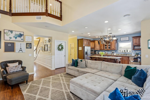 living room with an inviting chandelier, sink, hardwood / wood-style flooring, and a high ceiling