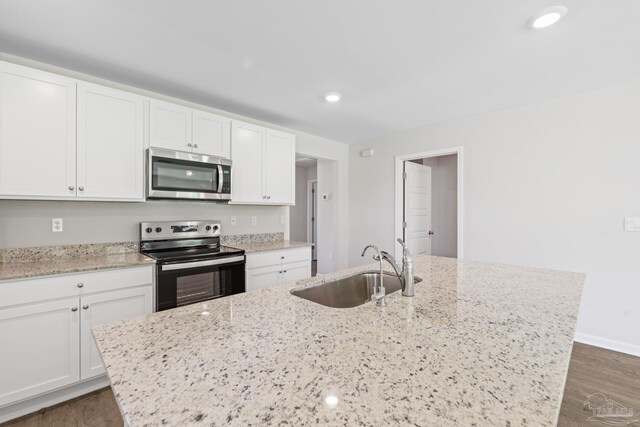 kitchen with dark wood-type flooring, sink, light stone countertops, white cabinetry, and stainless steel appliances