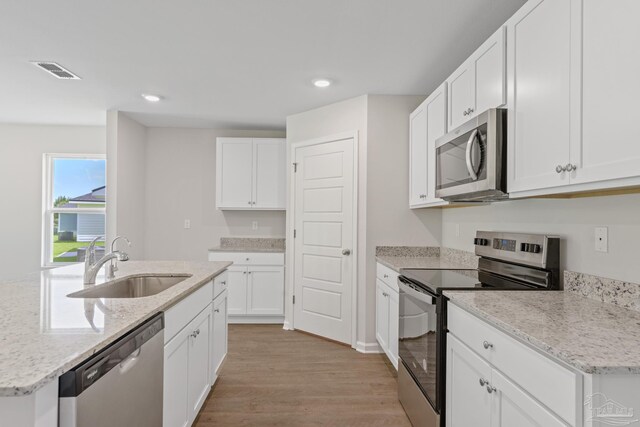 kitchen featuring sink, light wood-type flooring, appliances with stainless steel finishes, light stone counters, and white cabinetry