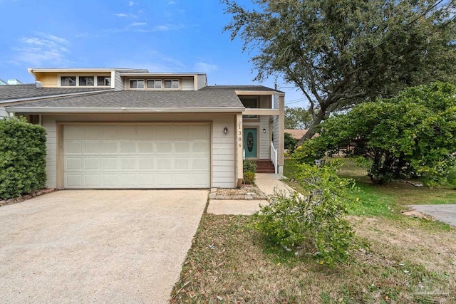 view of front facade with a garage, concrete driveway, and a shingled roof