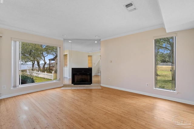 unfurnished living room with light wood finished floors, a fireplace, visible vents, and a wealth of natural light