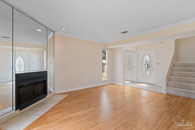 entrance foyer featuring a fireplace with flush hearth, visible vents, stairs, and wood finished floors