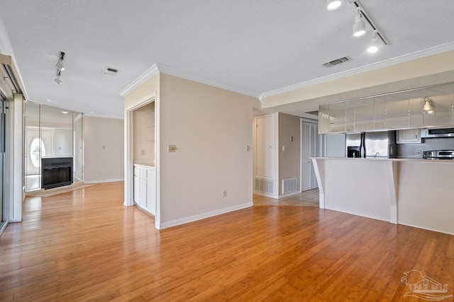 unfurnished living room featuring light wood-style flooring, visible vents, and crown molding