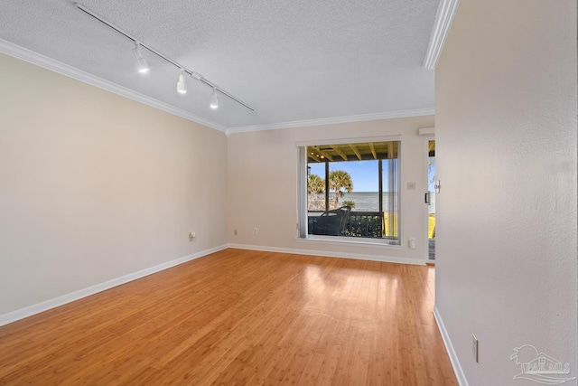 empty room featuring light wood-type flooring, crown molding, baseboards, and a textured ceiling