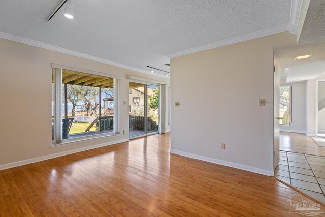 unfurnished room featuring a textured ceiling, light wood-type flooring, rail lighting, and crown molding