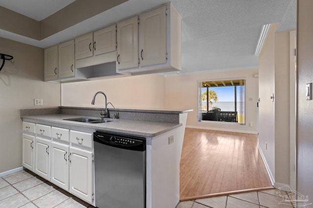 kitchen featuring baseboards, dishwasher, light wood-style flooring, a textured ceiling, and a sink