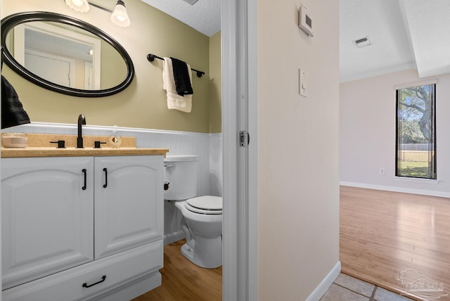 bathroom with visible vents, toilet, wainscoting, a textured ceiling, and wood finished floors