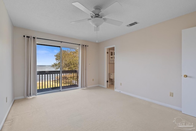 spare room featuring a textured ceiling, carpet floors, a ceiling fan, visible vents, and baseboards