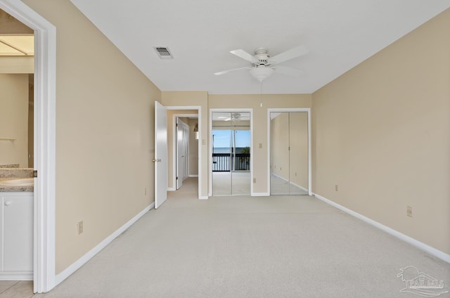 unfurnished bedroom with visible vents, connected bathroom, light carpet, and baseboards