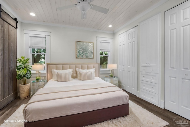 bedroom featuring wooden ceiling, multiple closets, dark hardwood / wood-style floors, ceiling fan, and a barn door