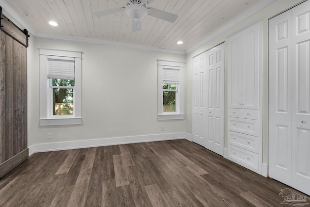 unfurnished bedroom with ceiling fan, a barn door, dark hardwood / wood-style flooring, and wooden ceiling