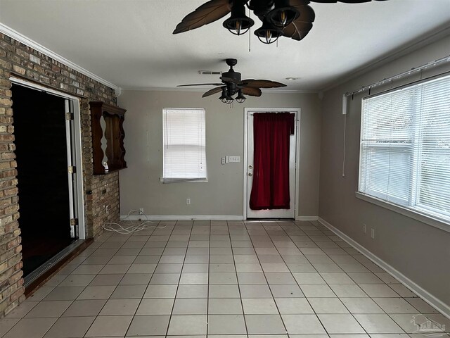 unfurnished living room featuring brick wall, ornamental molding, ceiling fan, and tile patterned floors