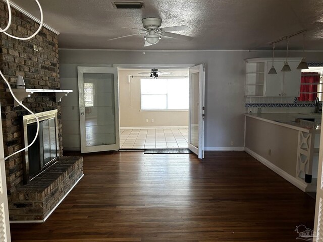 unfurnished living room with ceiling fan, a textured ceiling, a brick fireplace, and hardwood / wood-style floors