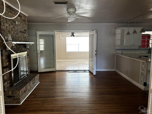 unfurnished living room with visible vents, ceiling fan, dark wood-style flooring, a textured ceiling, and a fireplace