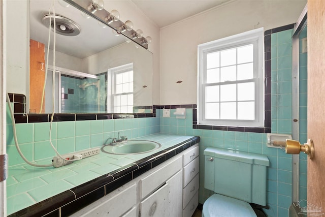 bathroom with vanity, walk in shower, toilet, and tile walls