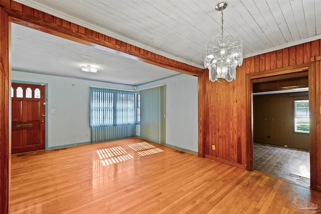 interior space featuring wooden walls, wooden ceiling, light hardwood / wood-style floors, crown molding, and an inviting chandelier