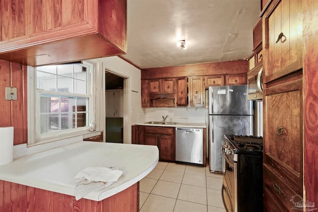 kitchen with light tile patterned floors, sink, kitchen peninsula, a kitchen breakfast bar, and appliances with stainless steel finishes