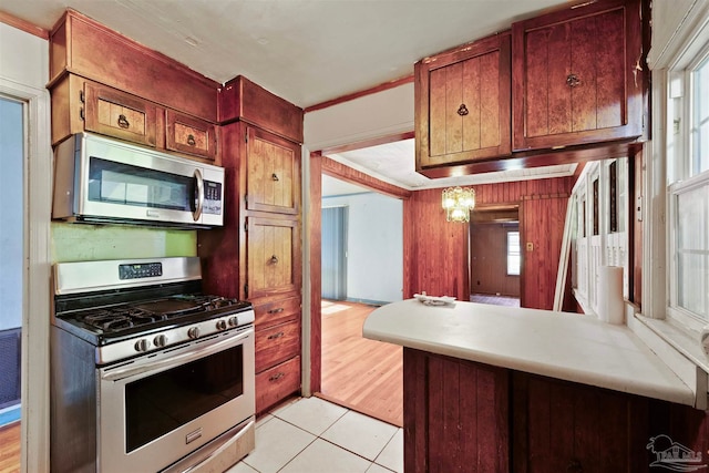 kitchen featuring appliances with stainless steel finishes, a healthy amount of sunlight, ornamental molding, and light hardwood / wood-style flooring