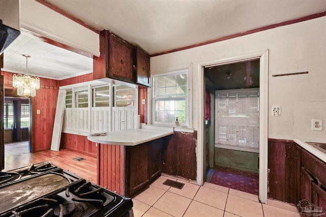 kitchen featuring wood walls, hanging light fixtures, light tile patterned floors, electric range, and an inviting chandelier